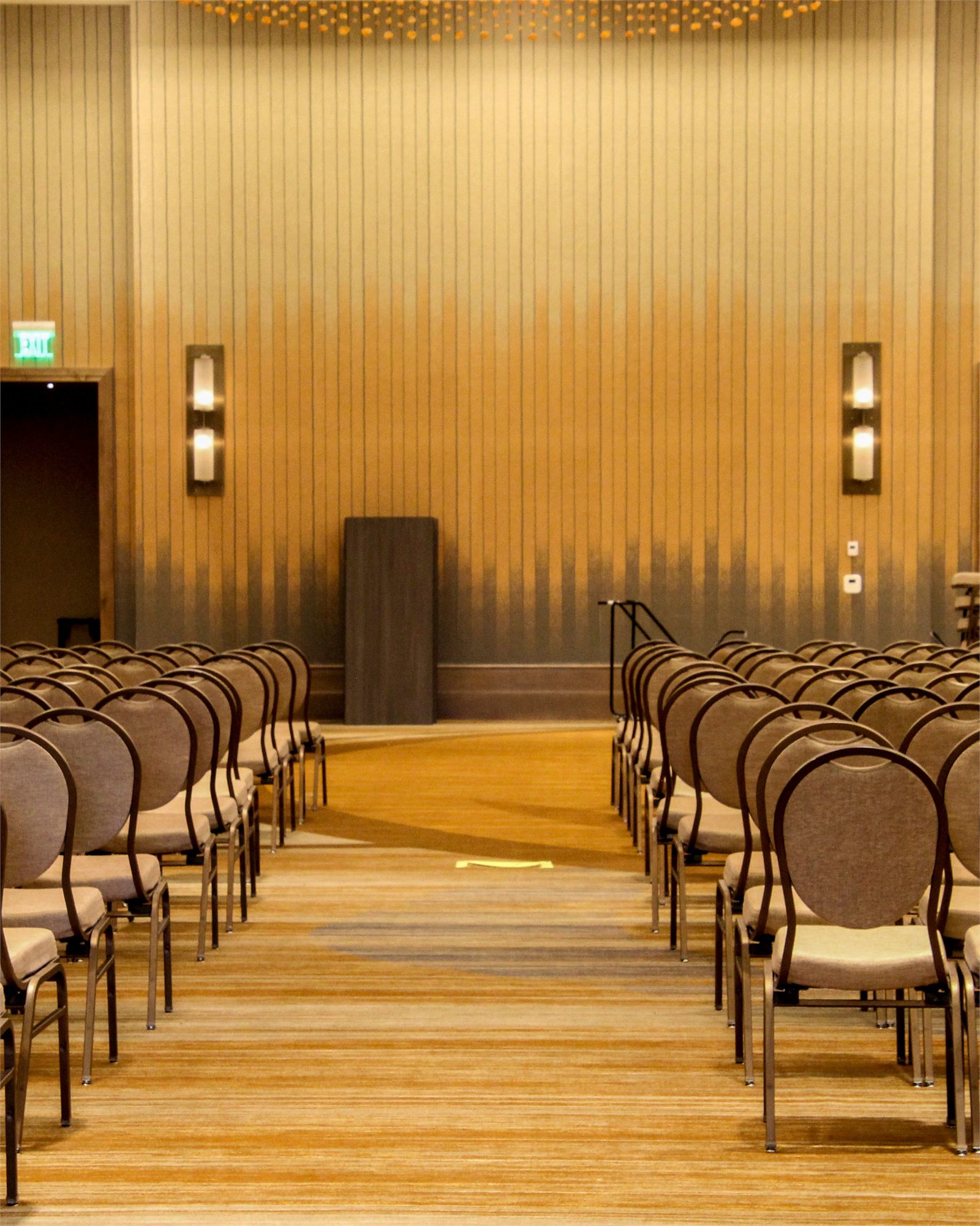 Rows of empty chairs facing a lectern in a conference hall before the delegates arrive