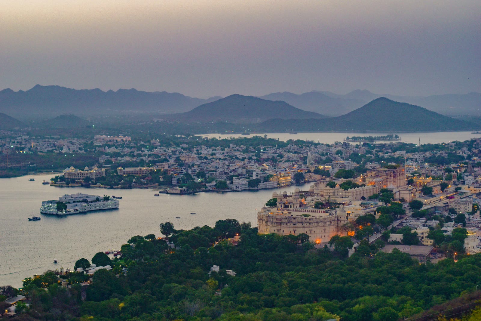 A lake city at twilight, its waterfront lit against the hills