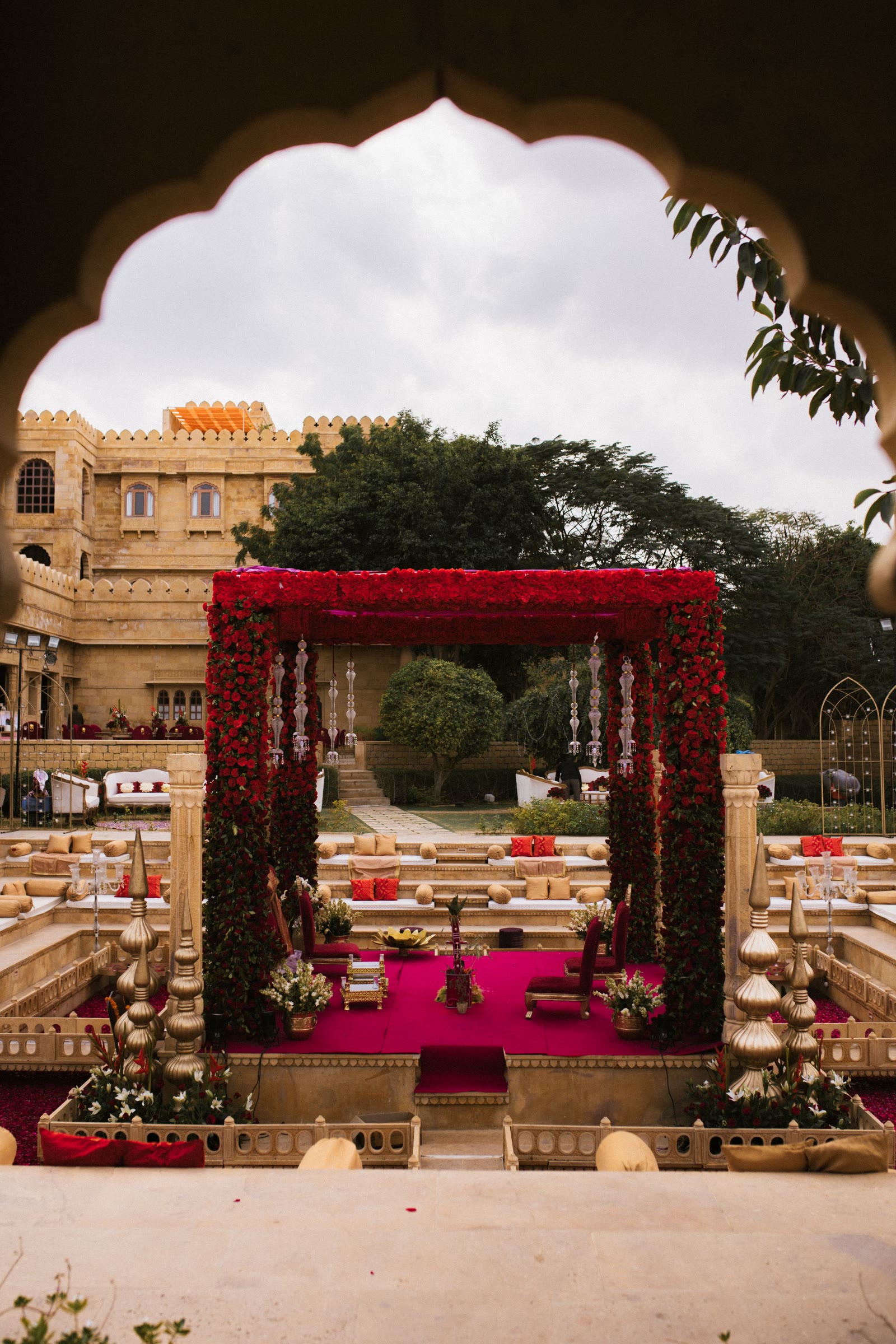 A rose-covered mandap set for a ceremony in a sandstone fort courtyard