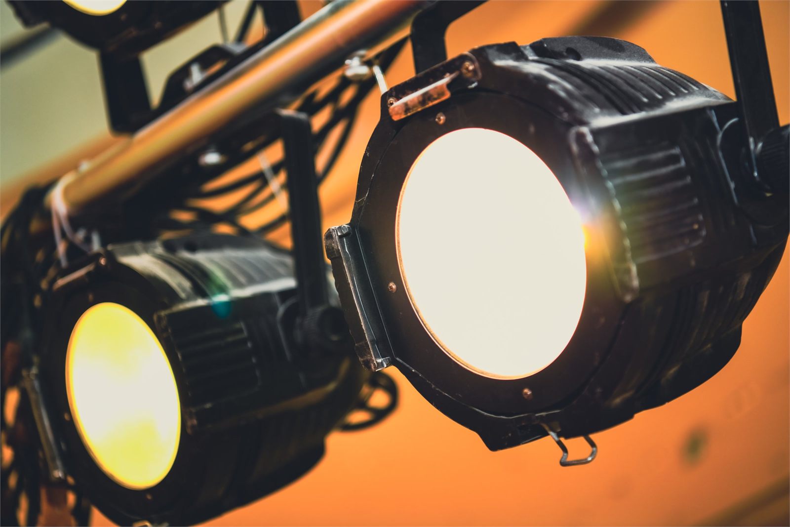 Two stage lanterns rigged on a truss, burning warm amber against a dark ceiling