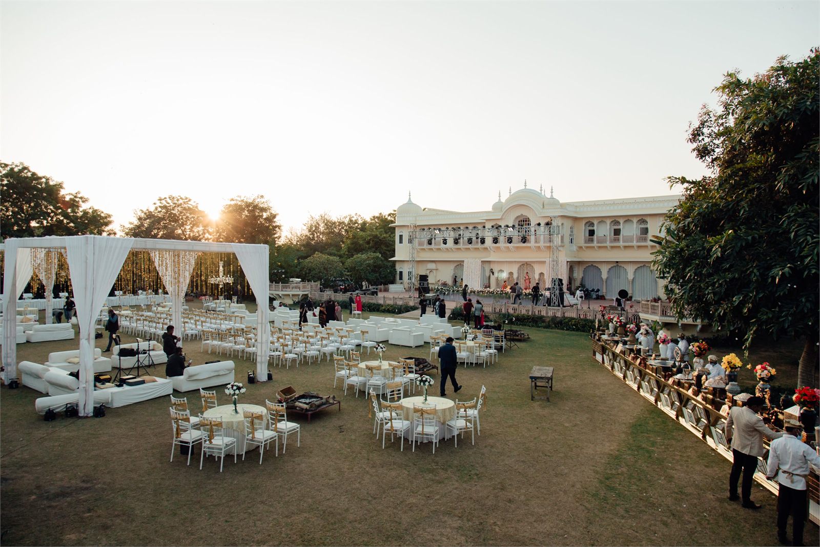 A venue lawn being dressed at sunset, chairs and seating being set out before an event