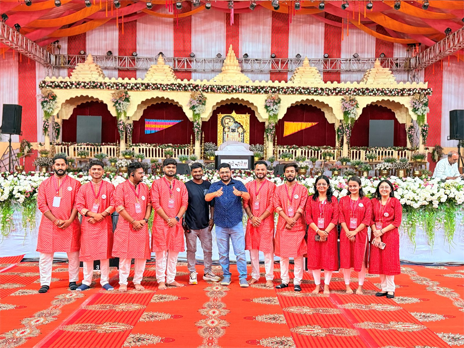 Indraa Events crew in red kurtas standing before a golden temple-style mandap stage