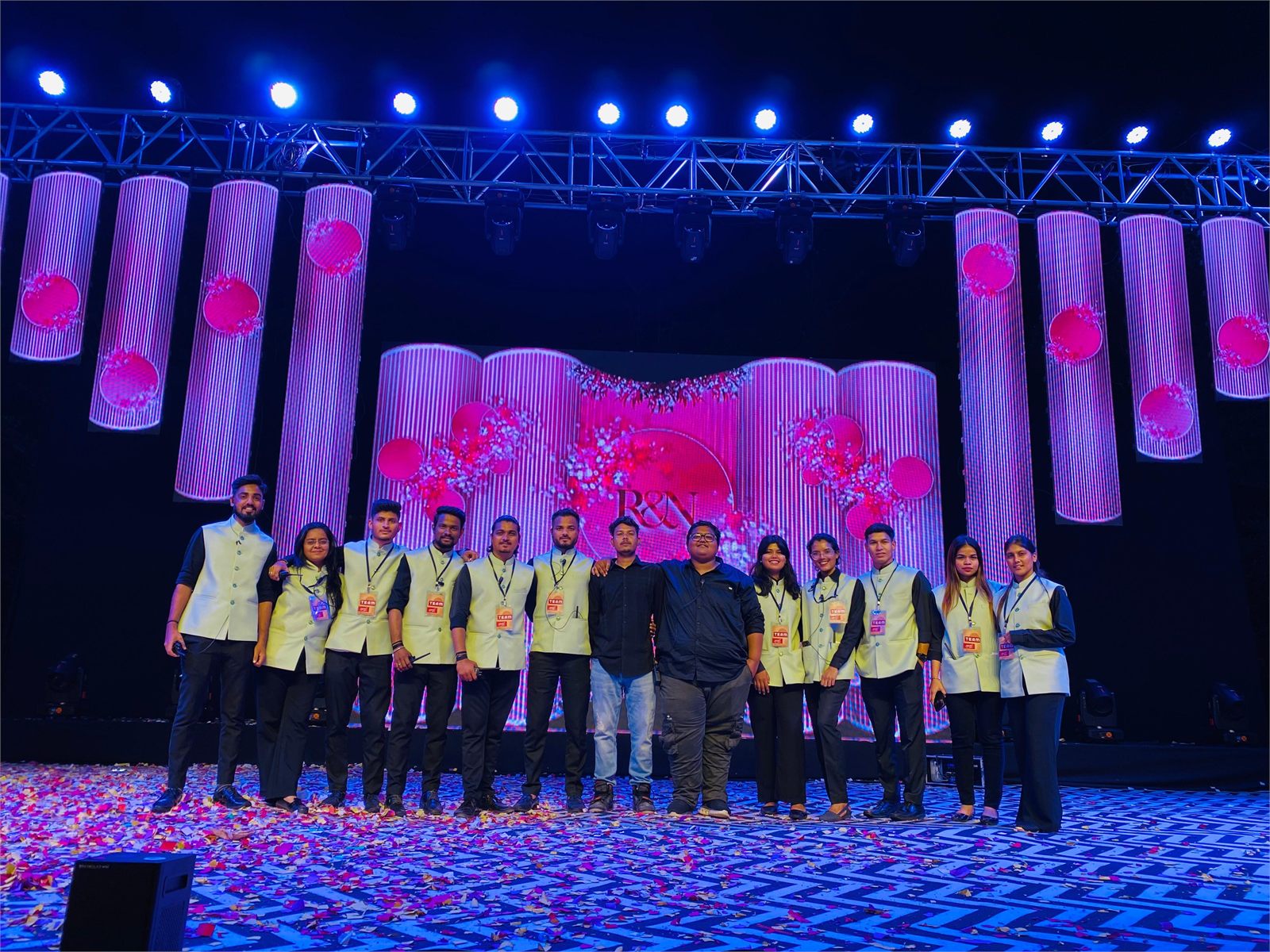 Indraa Events crew on a sangeet stage with an LED backdrop and confetti on the floor